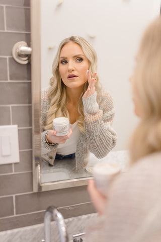 Brandi Gregge looking at herself in the mirror while using a product from the M&N skincare