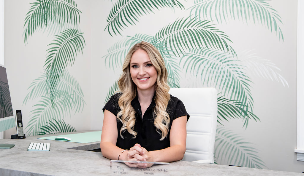 Brandi Gregge sitting in her office while smiling.