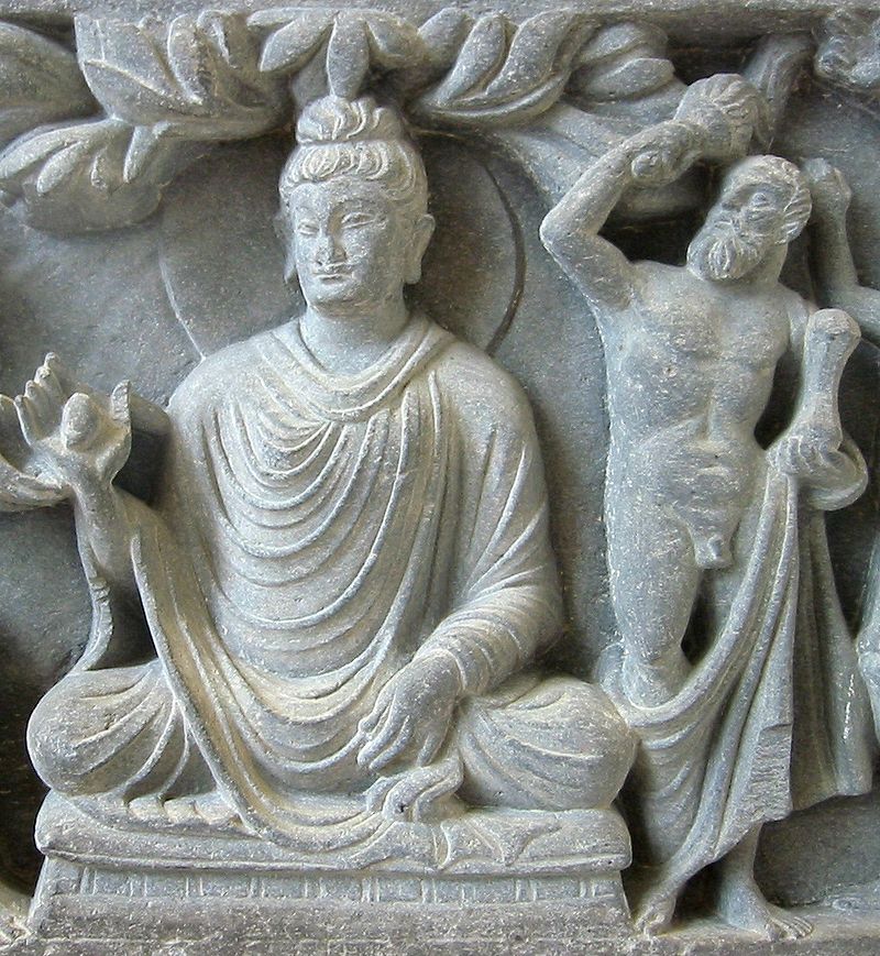 An Indian sculptural relief of Buddha, accompanied by the god Vajrapāni, who appears as a bearded, club-wielding, Heracles-like figure.