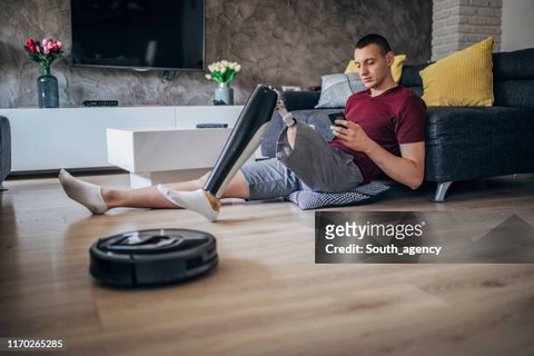 A man with disability Relaxing in the sitting room, while Robot vacuum is cleaning the floor for him. Courtesy gettimages via google