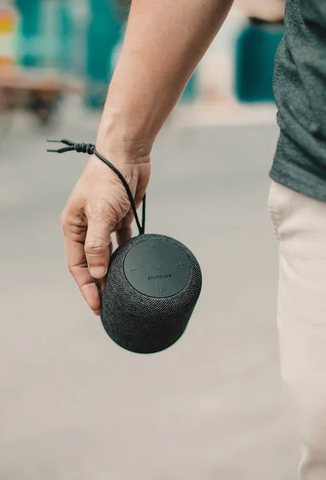 A man walking on the road listening to bluetooth speaker