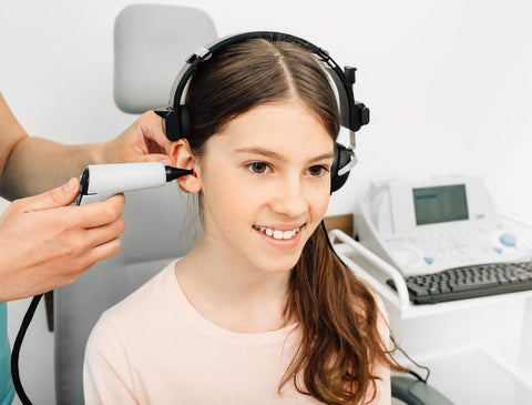 a girl is having a checkup to see if her ears are healthy