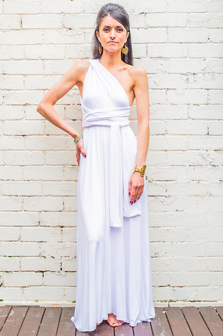 Model wearing a long dres in white, featuring a greek-inspired design