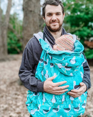 White male carrying a baby in a sling. Baby is covered in a seagull design BundleBean babywearing cover