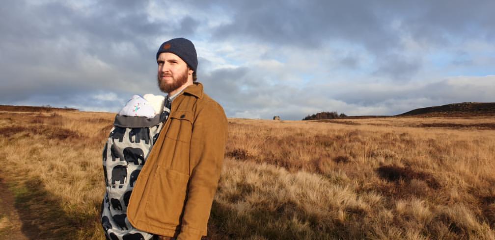 White male carrying a baby in a beautiful rugged landscape