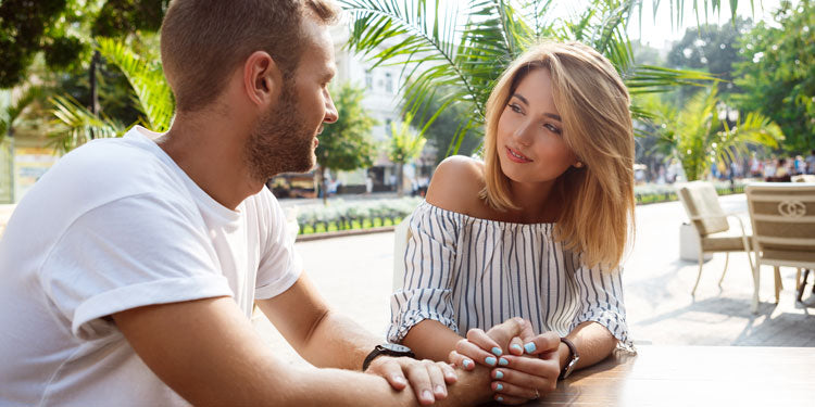 couple sitting in a park, smiling at each other and talking