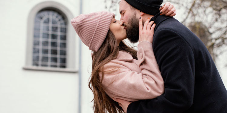 a young couple kissing; during winter; both are happy