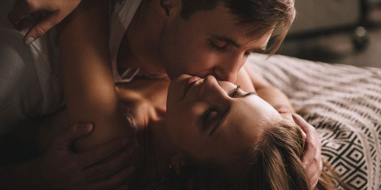 young couple laying in the bed and kissing, the man is on top