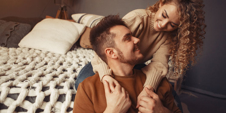 a woman hugs her man from behind and confidently smiles at him