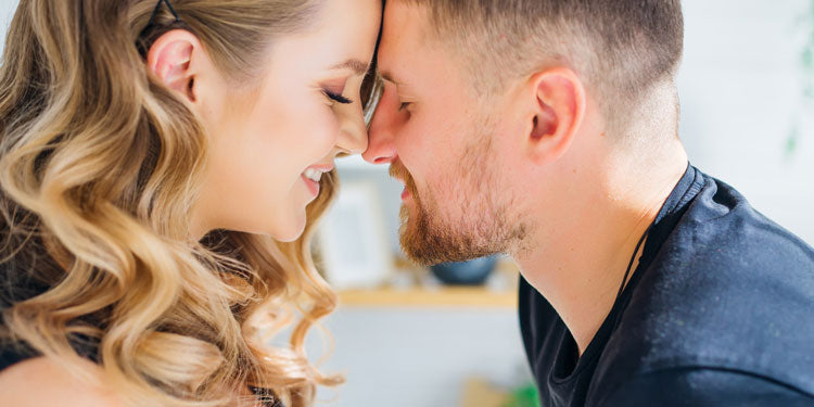 man and woman leaning toward each other as their foreheads touch; both look relieved and loving