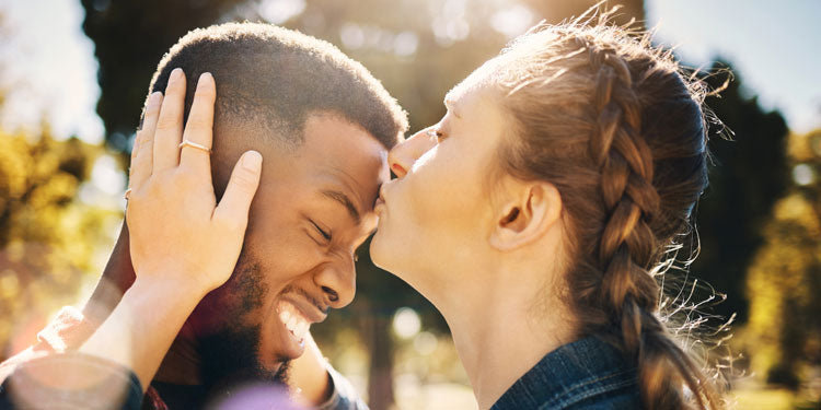 young woman compassionately kissing her boyfriend on the forehead