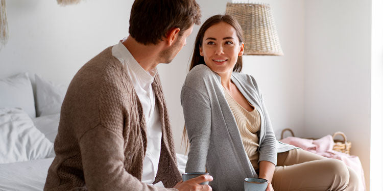 couple sitting on bed, talking and smiling