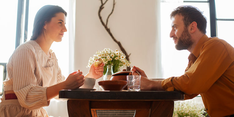 couple sitting at a table, eating and talking