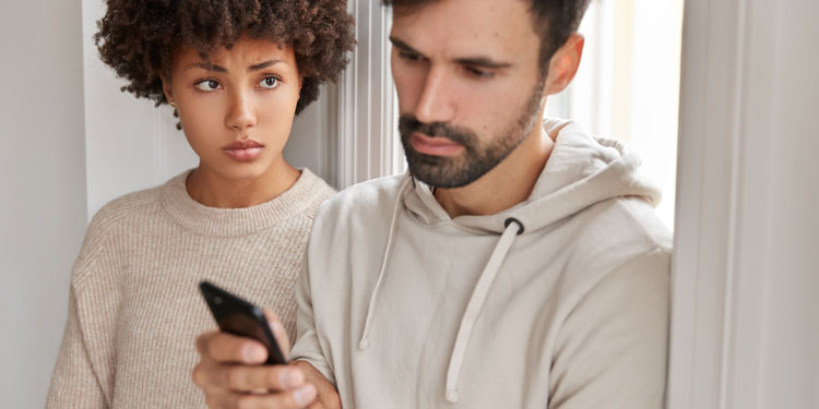 man is looking at his phone while avoiding his girlfriend