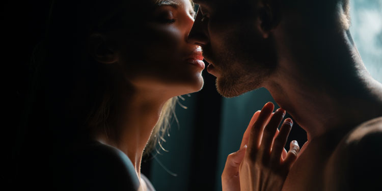 sensual photo of a man an woman kissing in a dimmed room