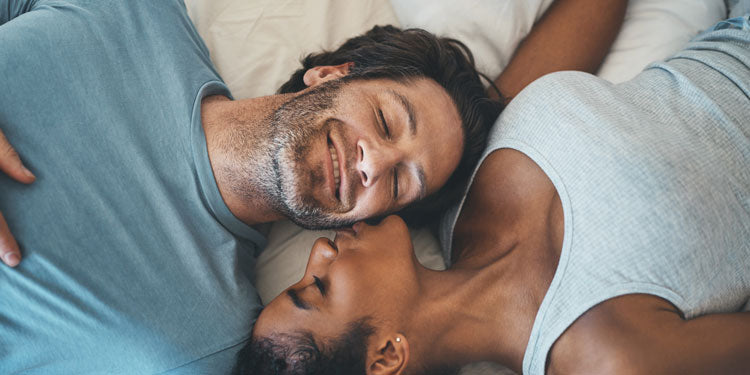 loving couple laying together, smiling, being happy, the woman kisses the man on the cheeks