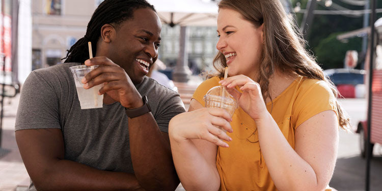 interracial couple sitting at a cafe, talking, drinking coffee and laughing