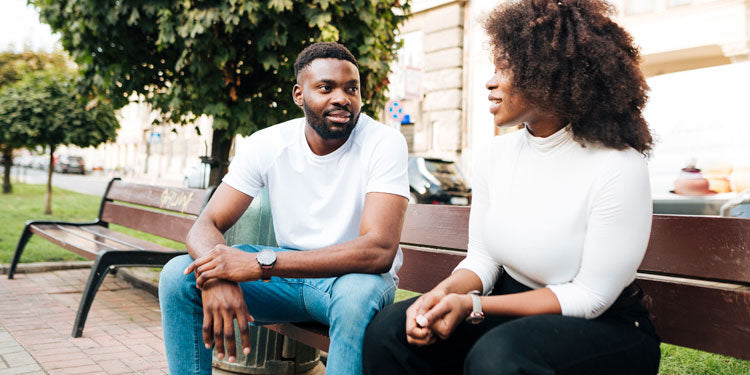 Afro-American couple sitting on a bench in a park and talking