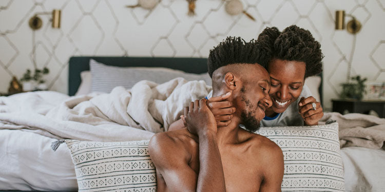 young couple sitting by the bed and cuddling