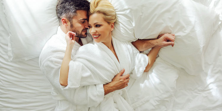 man and woman laying in bed with their spa coats on