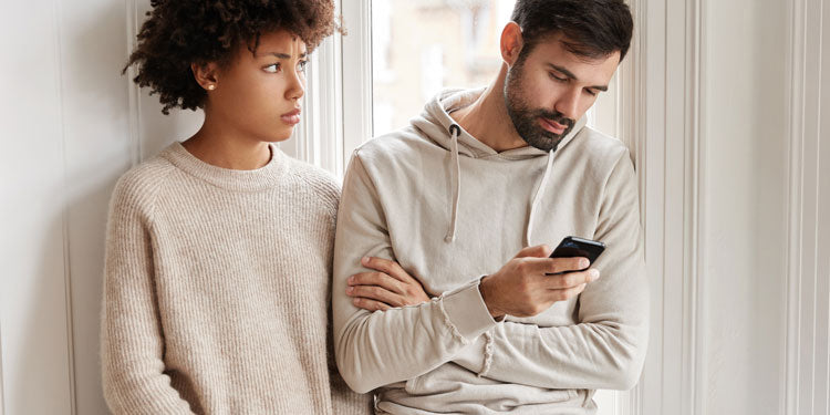 the man ignoring his girlfriend, the man looks at his phone while the woman is standing concerned