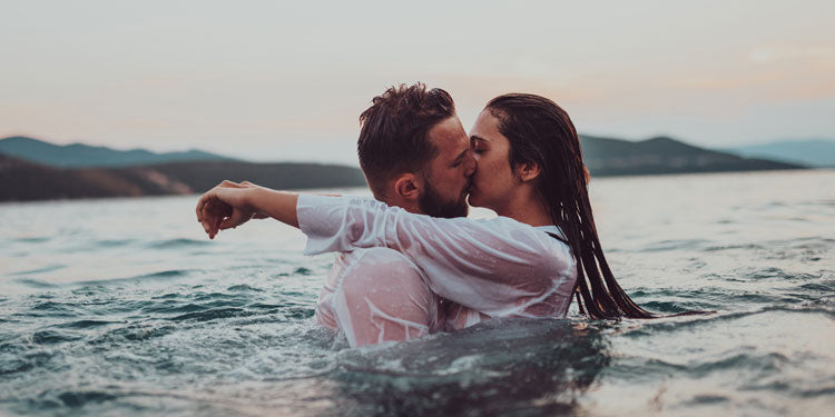 married couple being romantic in the water, both kissing