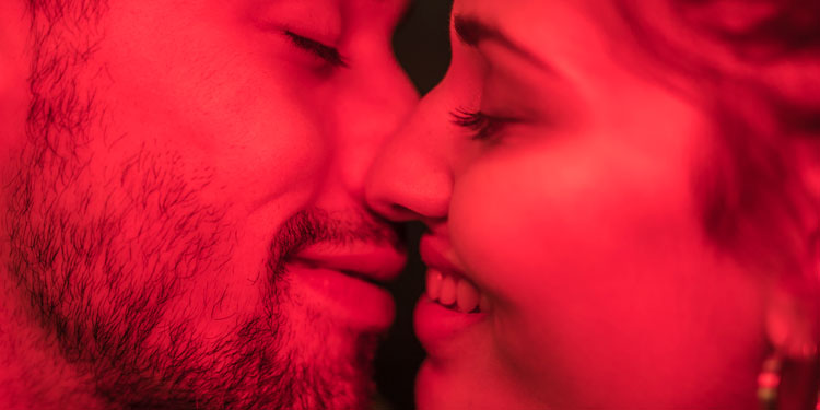 a close up of man an woman kissing, the picture is in red tones