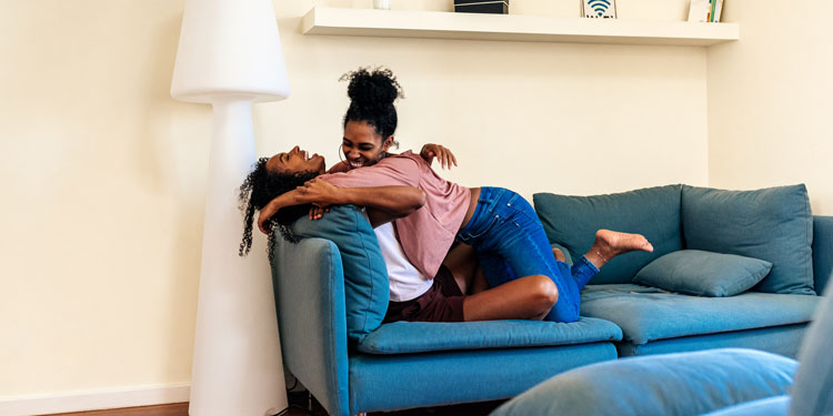 a young couple cuddling and smiling on a sofa