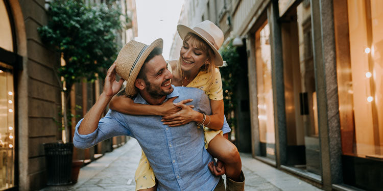 a young couple on a vacation, the woman is piggybacking on the man, both are happy and smiling