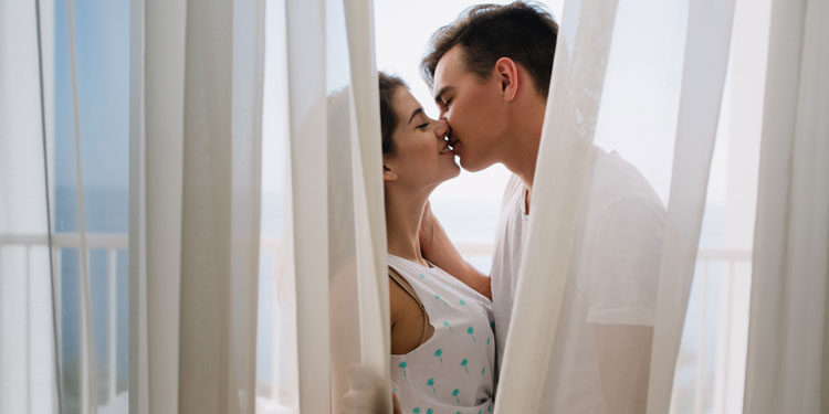 couple kissing behind white curtains, both are happy