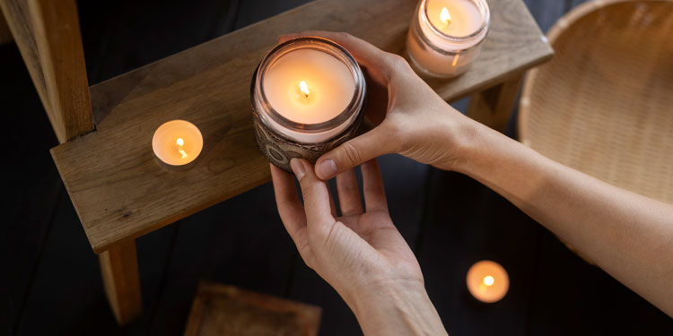 woman hands picking up a candle with wax in it