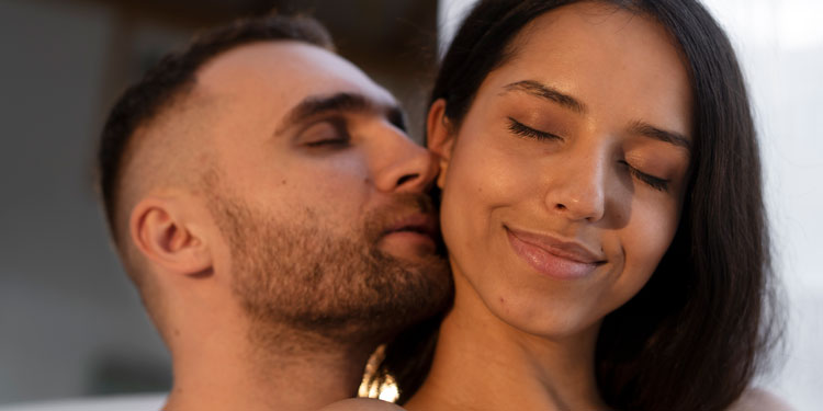 close up of a man and woman faces, the man cuddles his cheeks to hers