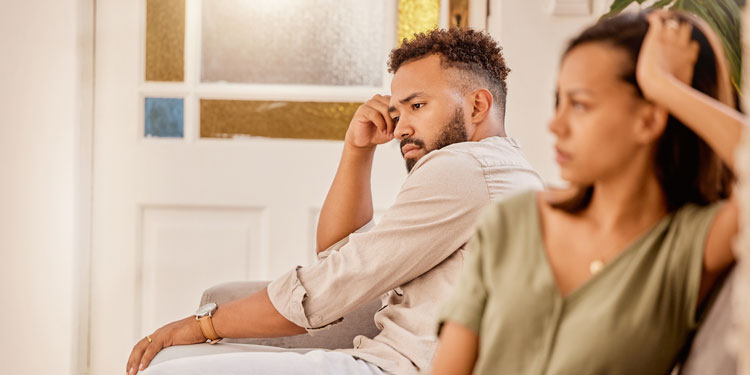 a young couple sitting on a couch and being mad or dissapointed with each other