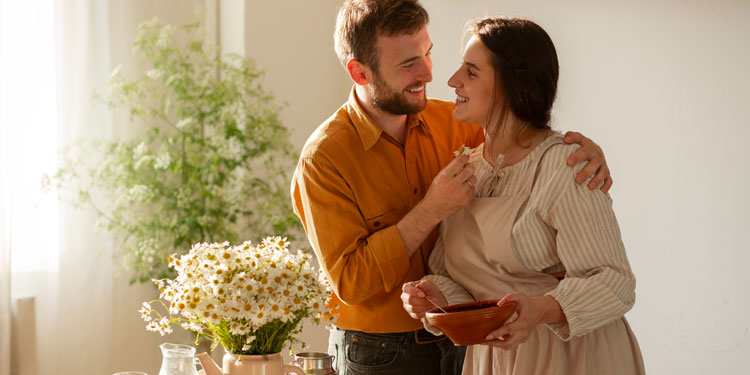 man and woman being playful and smiling, the woman holds a bowl of food