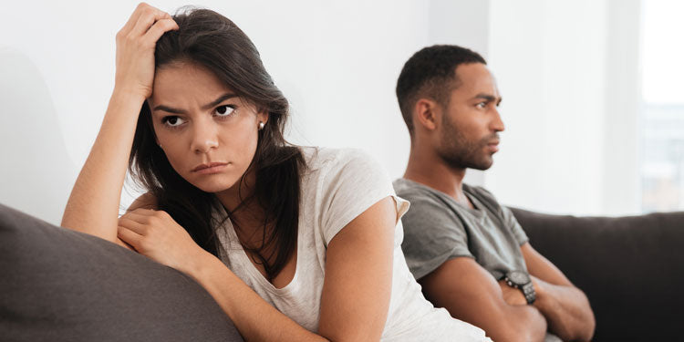 man and woman sitting on a sofa and looking disappointed or angry at each other