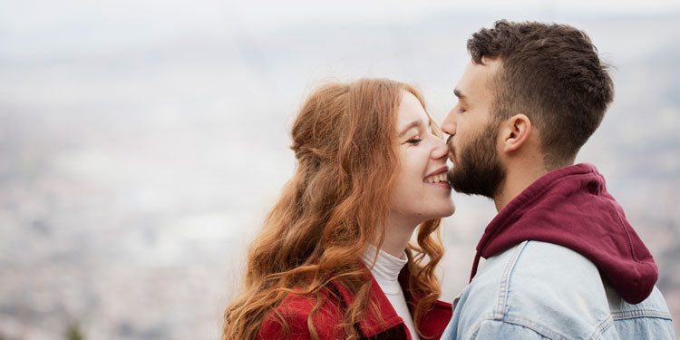 woman with red hair and man with black hair hugging an being loving together