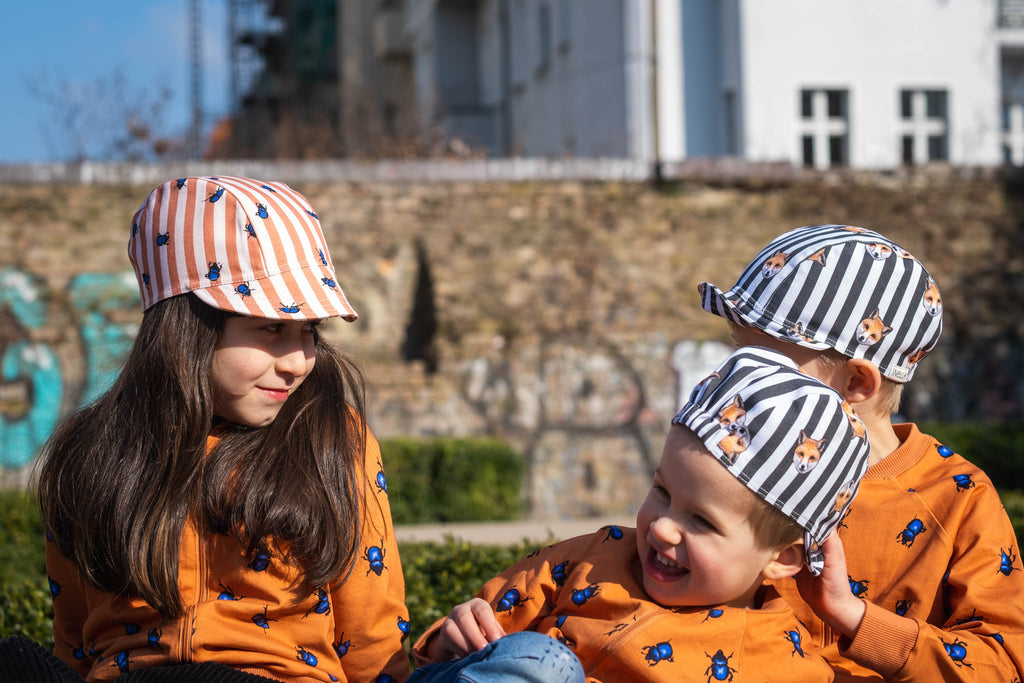 Children wearing beetle bomber jackets and bike caps