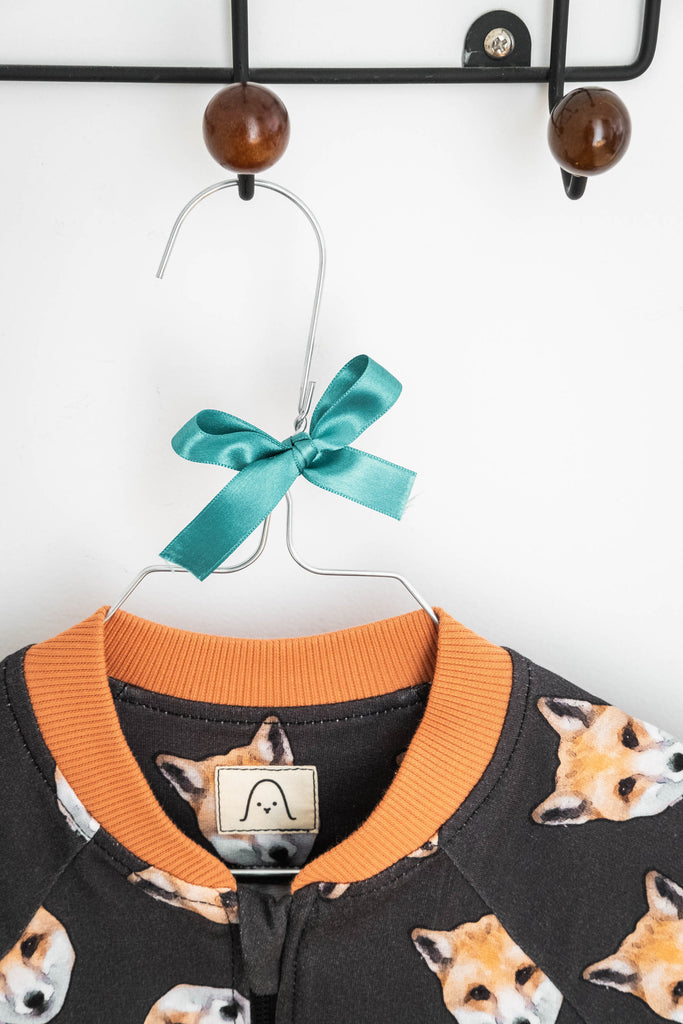 Donate clothes to charity when outgrown. Snella fox bomber jacket hanging on a coat hanger with ribbon