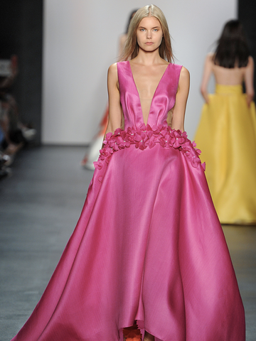 Model wearing bright pink gown on runway 