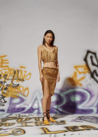 model wearing gold in front of black and gold graffiti wall 