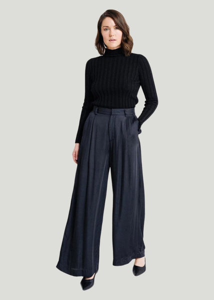 Model wearing Laude the Label Hepburn Pant in black satin with black turtleneck sweater