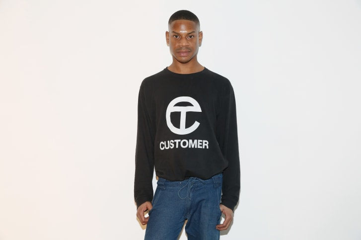 African American fashion designer Telfar Clemens wearing a sweater from his line Black owned brands Black History Month One Posh Closet