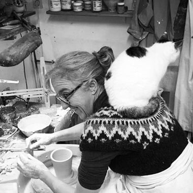 jonquil cook ceramic artist working in her studio with a cat sitting on her shoulders