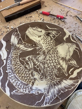 A platter in progress by Jonquil Cook using white slip over a brown/black stoneware clay body.