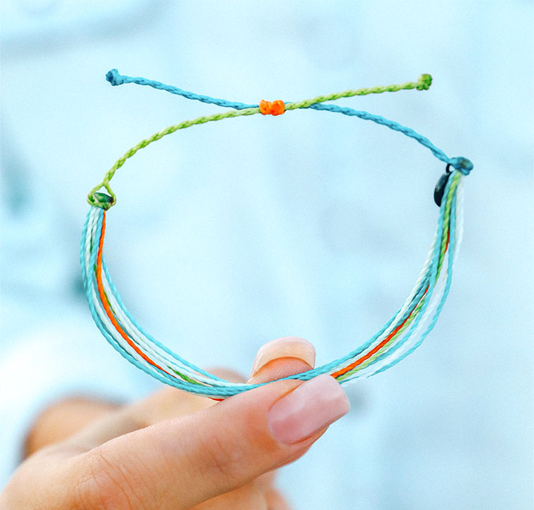 Hands wearing several Pura Vida charity bracelets