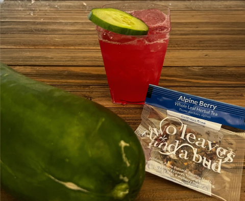 red cocktail drink garnished with cucumber slice, Two Leaves and a Bud Alpine Berry tea sachet