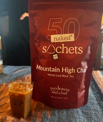 Two Leaves and a Bud Mountain High Chai pack of 50 sachets and a glass with a chai infused cocktail