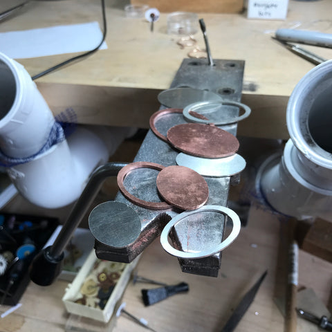 Recycled sterling silver and local copper pendant pieces sitting on Beth Millner work bench