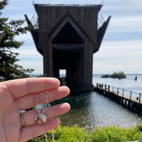 Conifer Couple Pendant from Beth Millner Jewelry in front of the Ore Dock