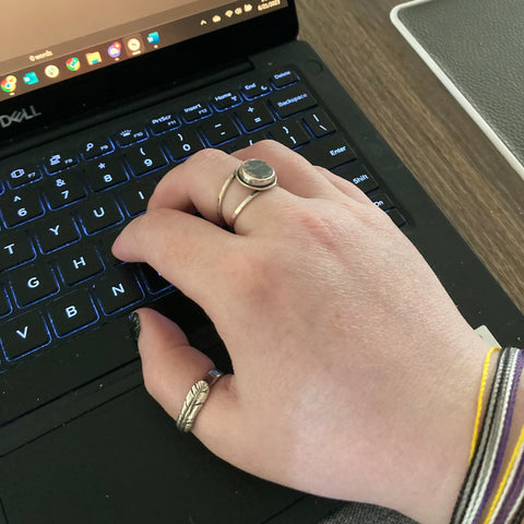 Ambassador Rebecca typing on a laptop wearing a stone ring and a custom quill ring from Beth Millner Jewelry